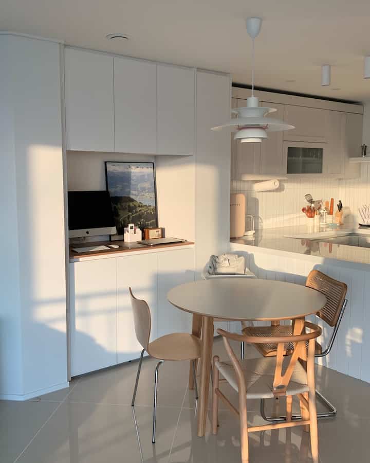 白と木目調が調和したキッチン空間、円形テーブルと異なる椅子が配置されたモダンでコンパクトな雰囲気