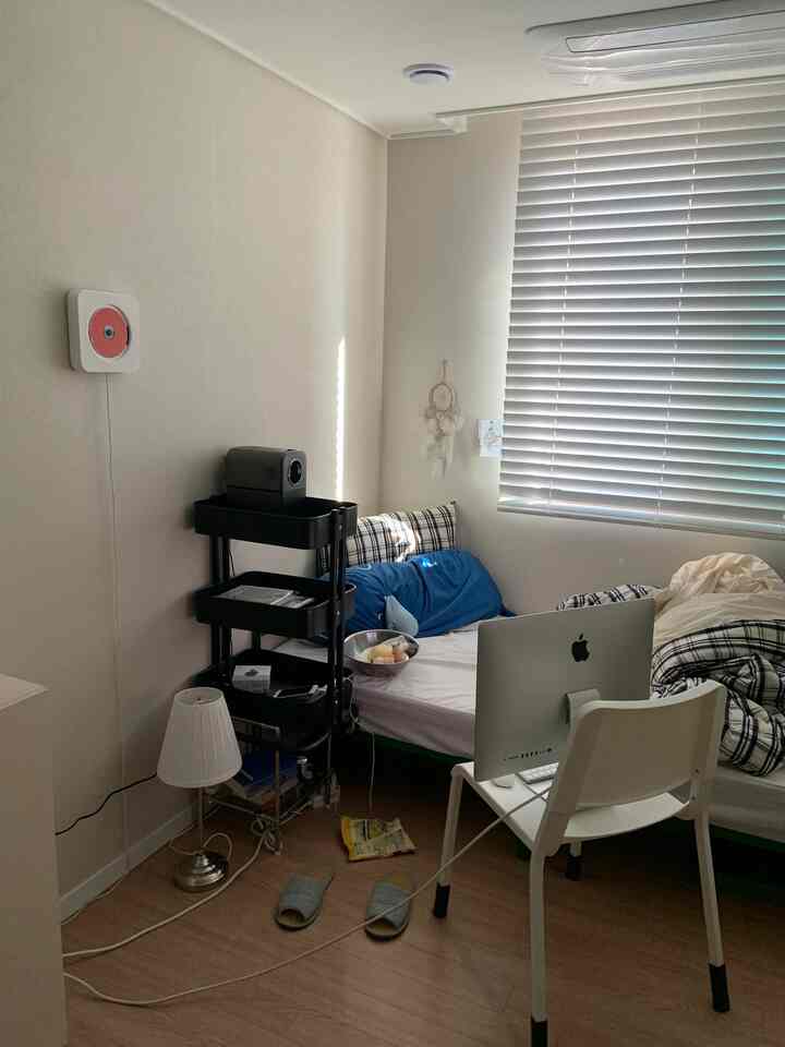 ホワイトと木目調の調和がとれたコンパクトな寝室、モダンな雰囲気のベッド、デスク、ブラインドを備えた空間