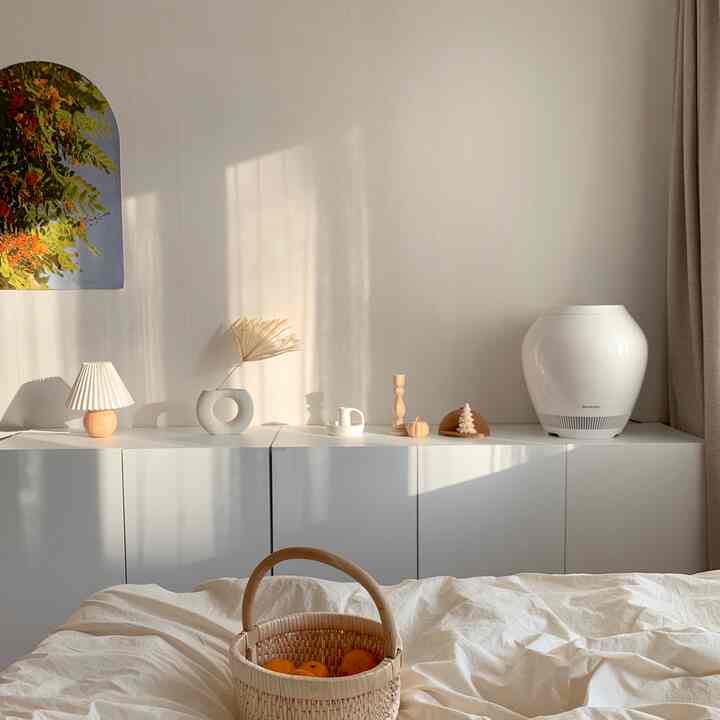 柔らかな白とベージュの寝室、すっきりとした白いキャビネットと自然素材の装飾が配置された落ち着いた空間