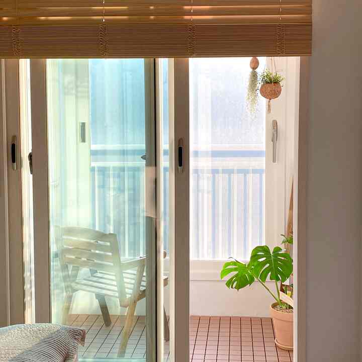 Natural-toned balcony featuring warm wood blinds and an outdoor wooden chair with lush green plant