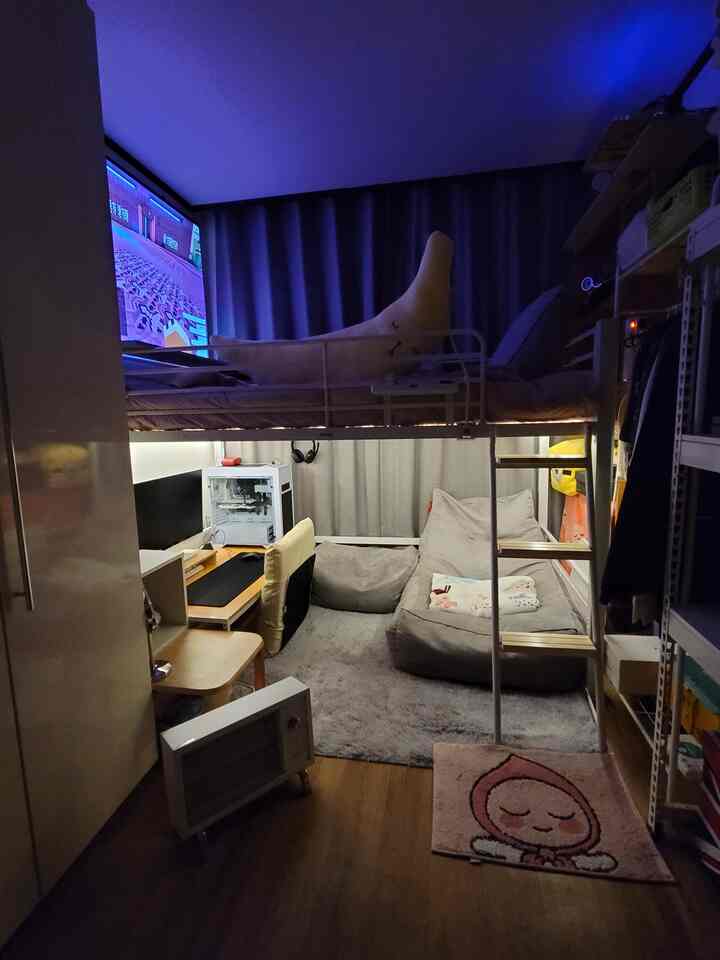Low-lit natural wood-toned small bedroom game room designed for single occupant