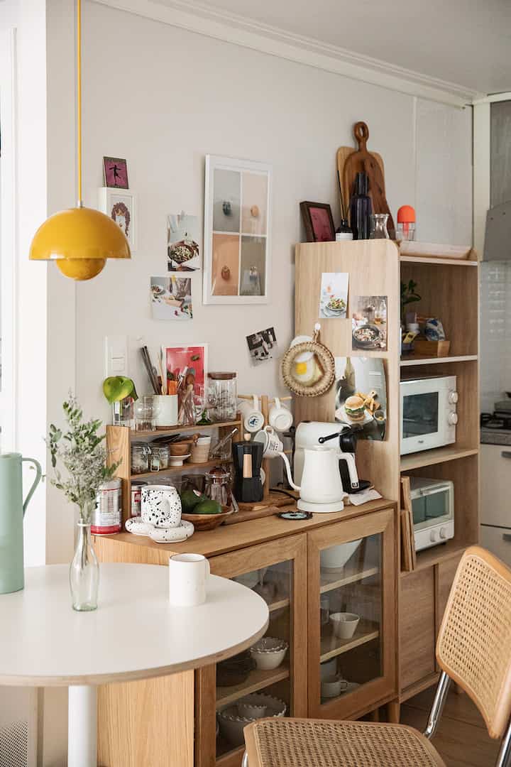 白と木目調が調和するキッチンスペース、丸テーブルと収納が整った雰囲気のあるおうちカフェ