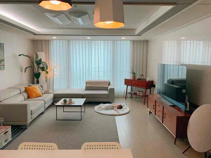 White and brown toned living room featuring a modular sofa and TV stand in a clean, spacious setting