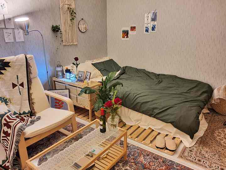 Natural-toned room featuring wooden furniture, a bed with green bedding, and cozy bohemian vintage living space for a single household
