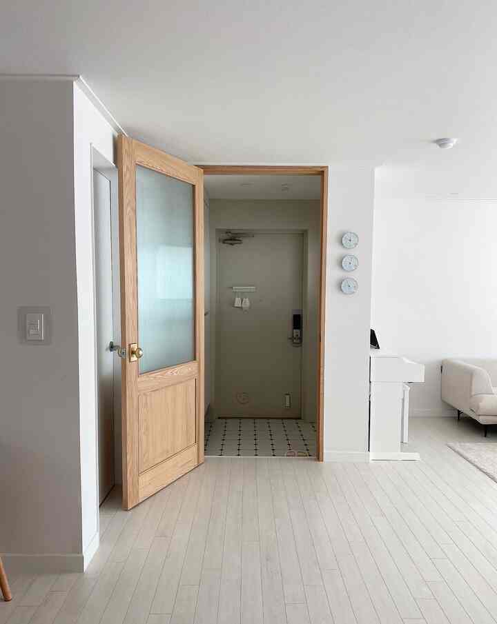 White and wood tone entrance and living room featuring a sofa with a simple, clean atmosphere
