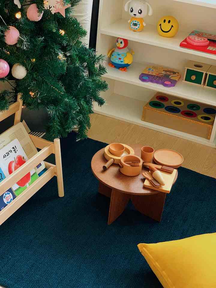 Kids' room with navy rug and natural wood stool, featuring playful toys and bookshelf creating cozy atmosphere