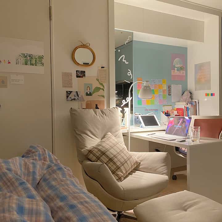 Neutral beige-toned compact studio living space featuring a single recliner sofa and a desk with workspace setup