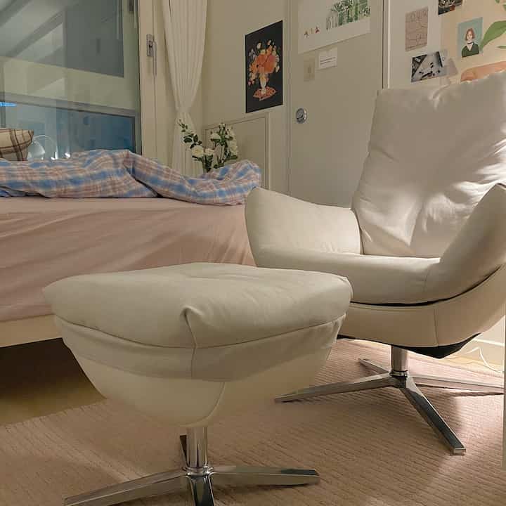 Cozy single-person bedroom featuring warm beige and ivory tones with an armchair and bed creating a natural atmosphere