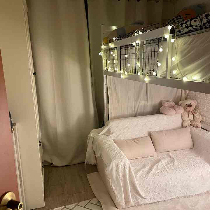 白とベージュのトーンのコンパクトな寝室、二段ベッドとソファベッド、ストリングライトが配された雰囲気のあるインテリア