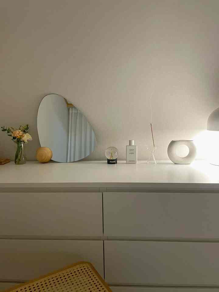 White-toned vanity featuring an organic-shaped mirror and neatly arranged accessories in a modern space