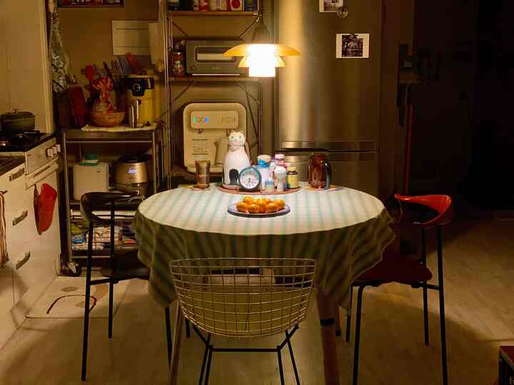 Kitchen space under warm lighting featuring a dining table with light green striped tablecloth and surrounding chairs creating a cozy atmosphere
