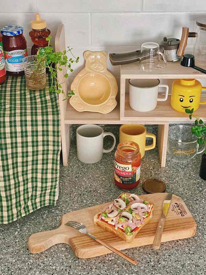 Natural wood tone kitchen with yellow accents featuring shelves, kitchen utensils, and a cutting board with food in a warm atmosphere