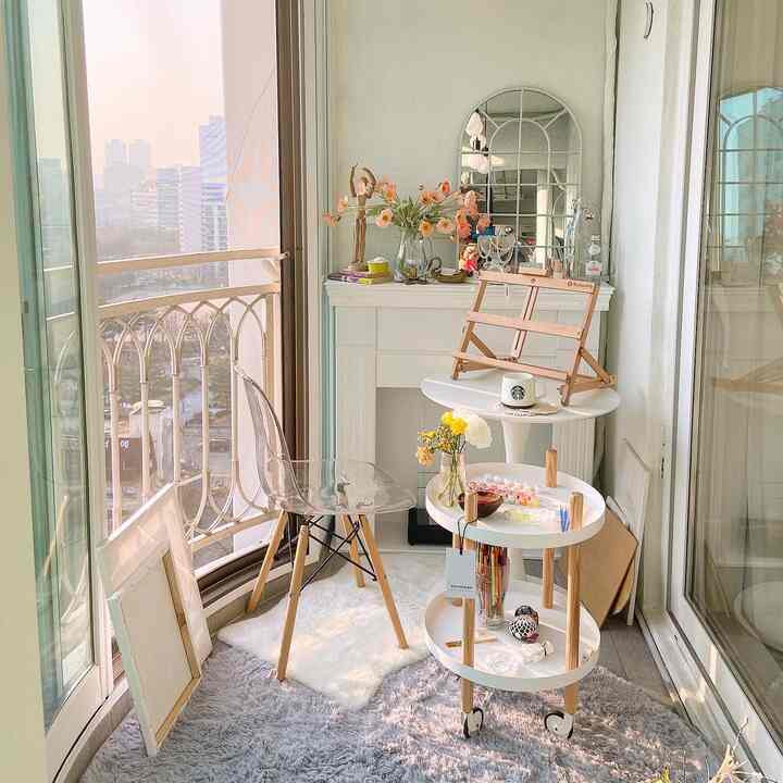 Bright veranda space featuring a transparent chair and white wood-tone furniture in a Mid-Century Modern styled workspace interior