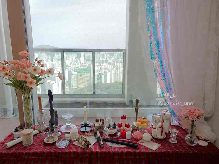White and red tone balcony space featuring a table runner decorated with various Christmas-themed candles and ornaments creating a cozy atmosphere