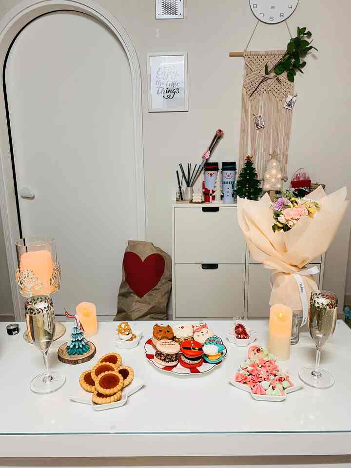 White and beige toned kitchen space featuring Christmas trees, candles, and a vase with flowers in a modern decor setting