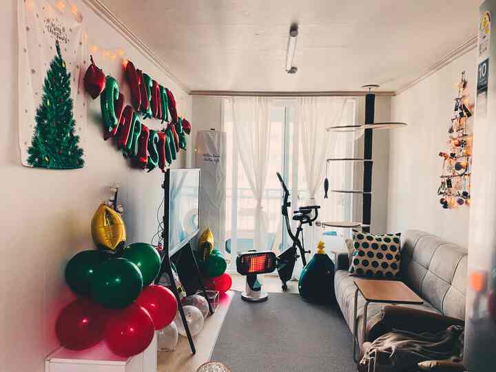 ベージュとホワイトのトーンで統一された、クリスマス装飾のあるリビング、ソファとキャットタワーが配置された居心地の良い空間