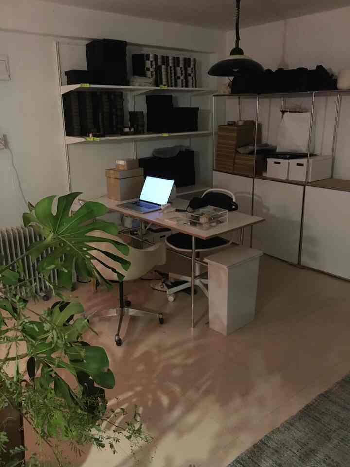 Modern compact home office space in white and beige tones, featuring plants and organized storage with a clean aesthetic