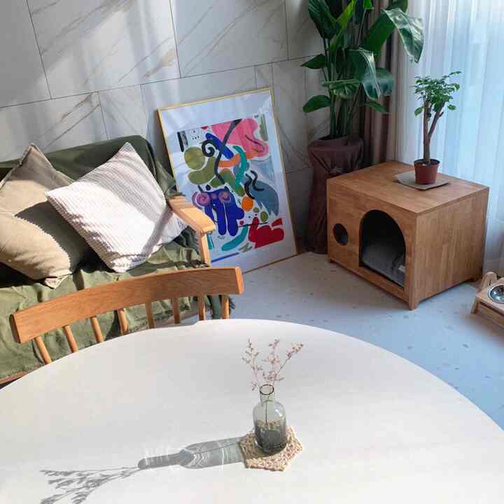 White and wood tone natural style living room featuring sofa, round table, and pet house in a cozy interior