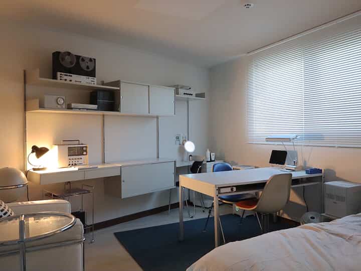 White and blue toned home office featuring Vitsoe shelving and Eames chair, a neat and modern compact workspace