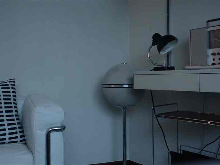 White and black toned living room corner featuring an armchair and floor lamp in a minimalist home office setup
