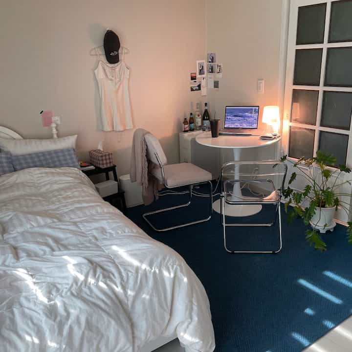 A 6-tatami bedroom in white and blue tones featuring a simple bed, round table with laptop, and workspace setup for remote work