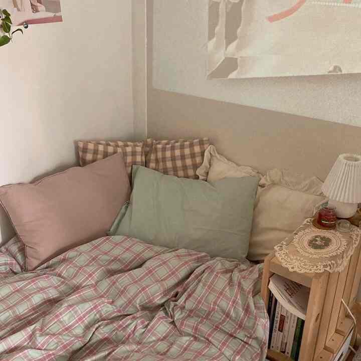 Mint and pink toned bedroom featuring a wooden bed with check-pattern duvet cover and multiple pillows creating a cozy atmosphere