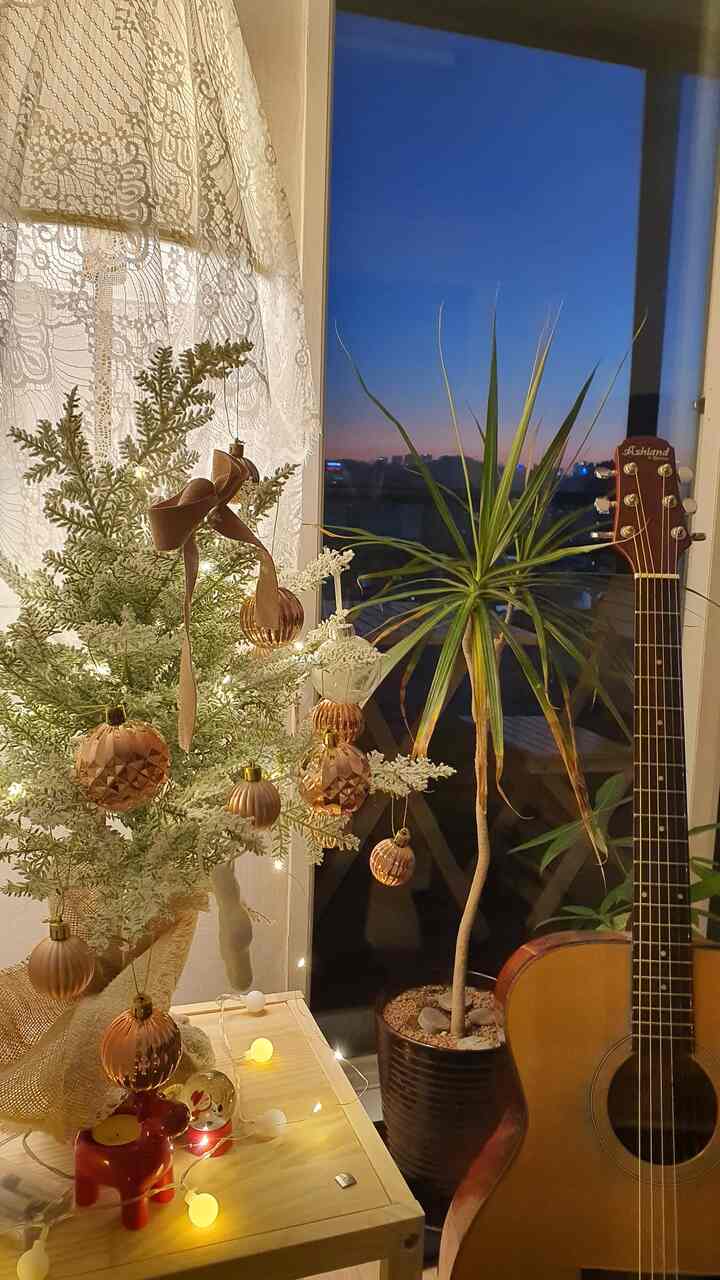 ウッドトーンとグリーンのリビング、クリスマスツリーとギターが置かれた温かみのあるインテリア