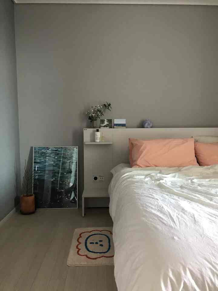 White and brown toned bedroom featuring a white bed with light pink pillows in a cozy and simple setting