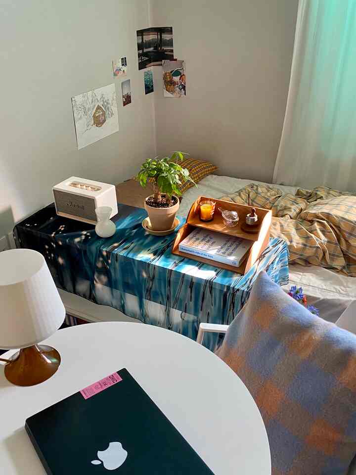 黄色チェックの寝具とヴィンテージの小物が調和したワンルーム、柔らかな自然光が入る温かみのあるインテリア