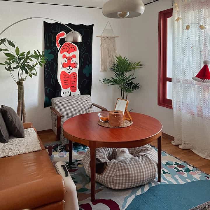 Living room in brown and white tones featuring a round table, sofa, and cat bed creating a natural and cozy atmosphere