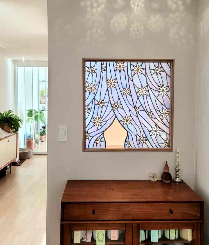 Bright entrance with white walls and wood tone sideboard, featuring a stained glass window beautifully filtering light, creating a natural atmosphere