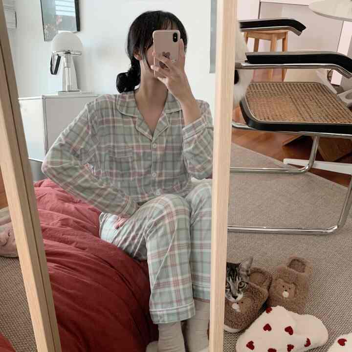 Natural living room with wood tone floors and beige rug, large wooden framed mirror, armchair, and a cat creating a cozy atmosphere