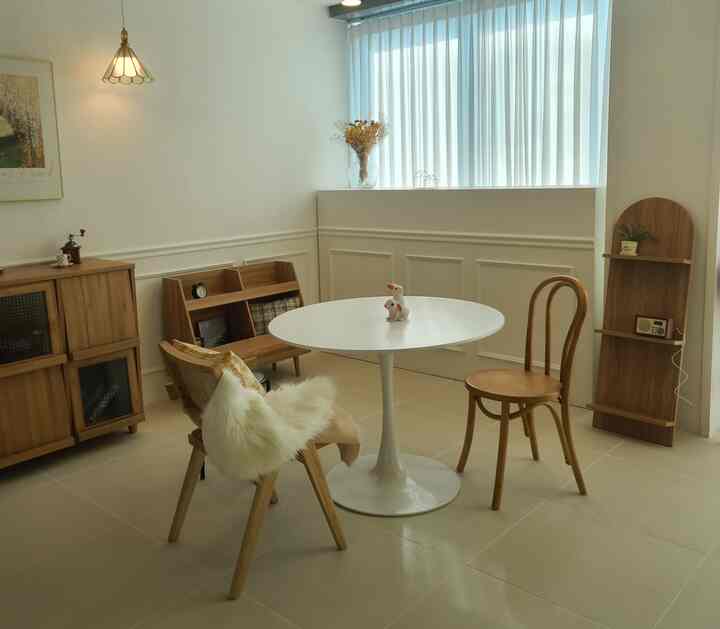 Dining room with white and wood tones featuring a round dining table and two wooden chairs in a simple setting