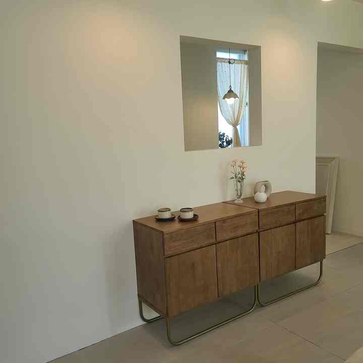 Natural tone living room corner with a brown sideboard, accented by sheer curtains and decorative objets creating a calm ambiance