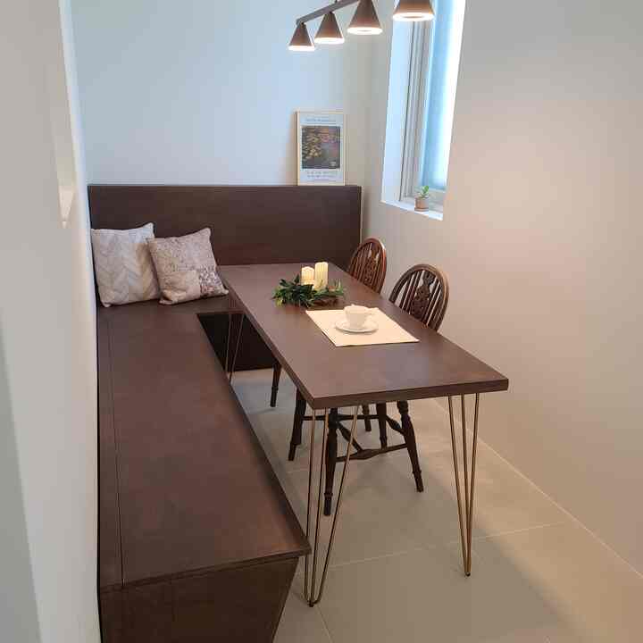 Natural-toned dining room with white walls, dark brown wooden dining table and bench, accented with cushions and candles for a cozy atmosphere