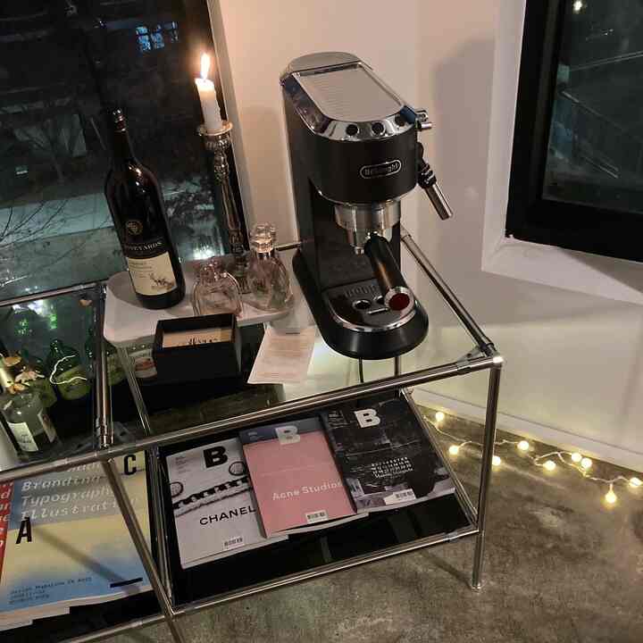 Modern kitchen space featuring a silver metal frame table with a coffee machine, candle, and wine bottle, complemented by warm string lights and cozy atmosphere