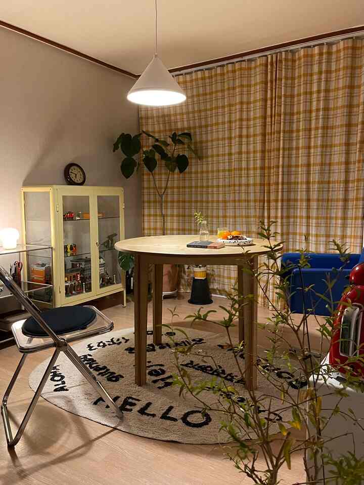 Cozy dining space with yellow check curtains and wooden round table, featuring modern furniture and warm lighting