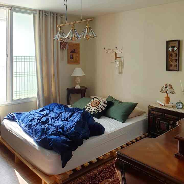 Beige-toned bedroom featuring a wood-tone low bed and vintage furniture creating a cozy atmosphere