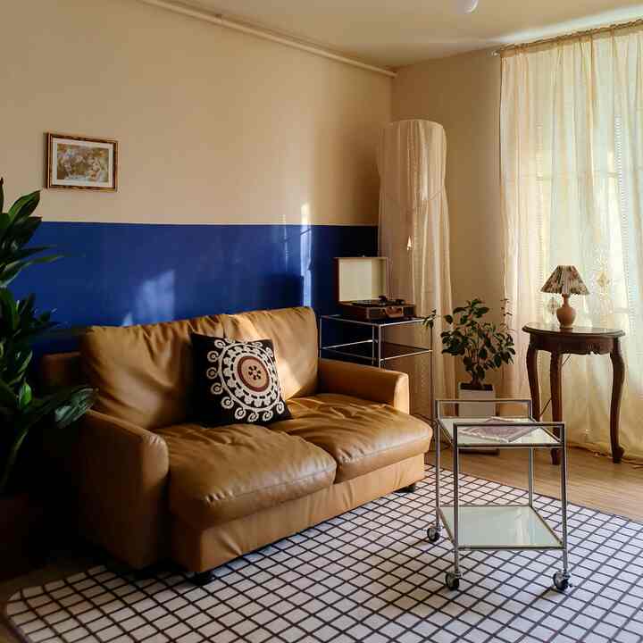 ベージュとネイビーブルーのリビング、キャメルブラウンのソファとヴィンテージ家具が配された雰囲気のある空間