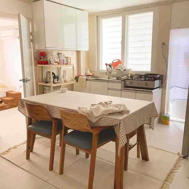 Warm beige and white toned veranda and kitchen space featuring large wooden dining table and chairs in a cozy multipurpose room