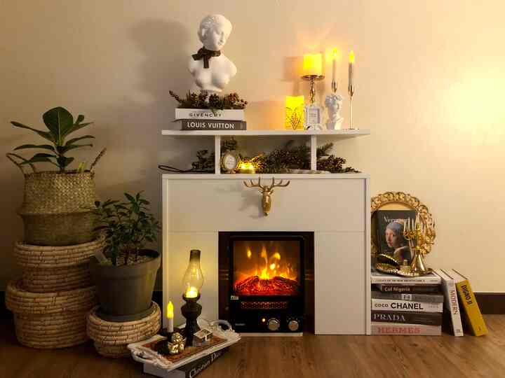 Classic style living room featuring a white fireplace console with gold accents, decorated with Christmas ornaments and plants for cozy ambiance