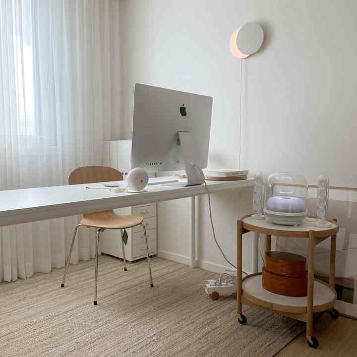 A clean home office in white and wood tones, featuring a long desk and Harman Kardon Soundsticks 4 speaker setup.