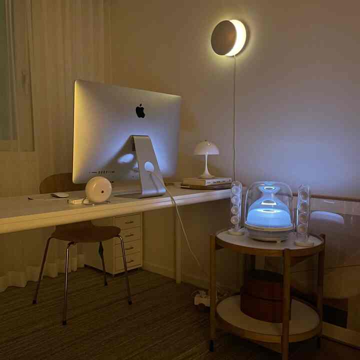 Warm white and wood tone home office featuring a large monitor and speakers, creating a cozy work atmosphere