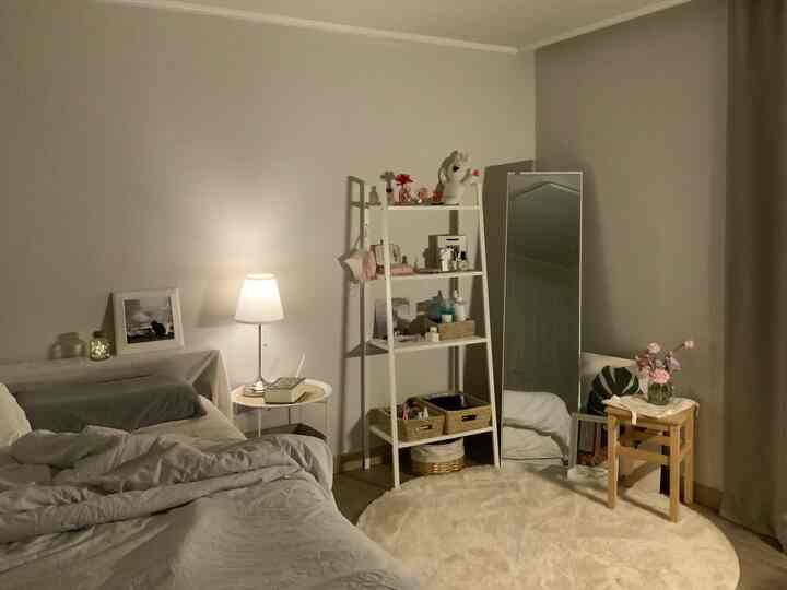 Natural-toned bedroom featuring bed and nightstand lamp creating a cozy and simple atmosphere