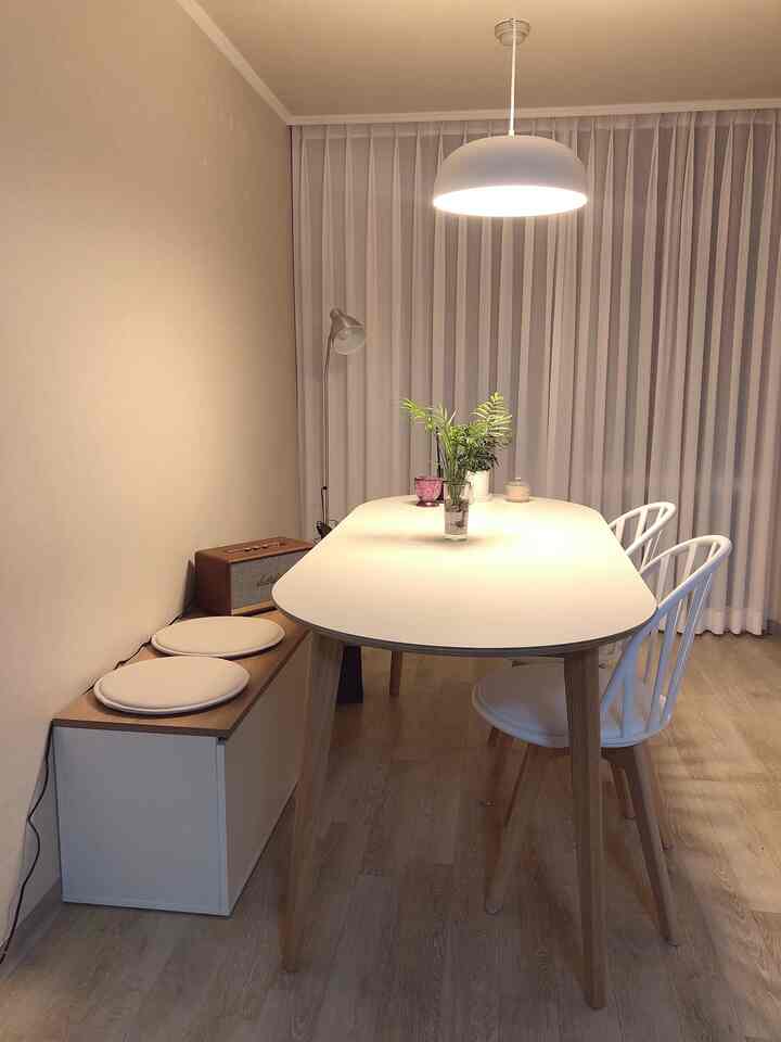 White and wood tone dining room featuring a dining table, bench, and curtains with a cozy atmosphere