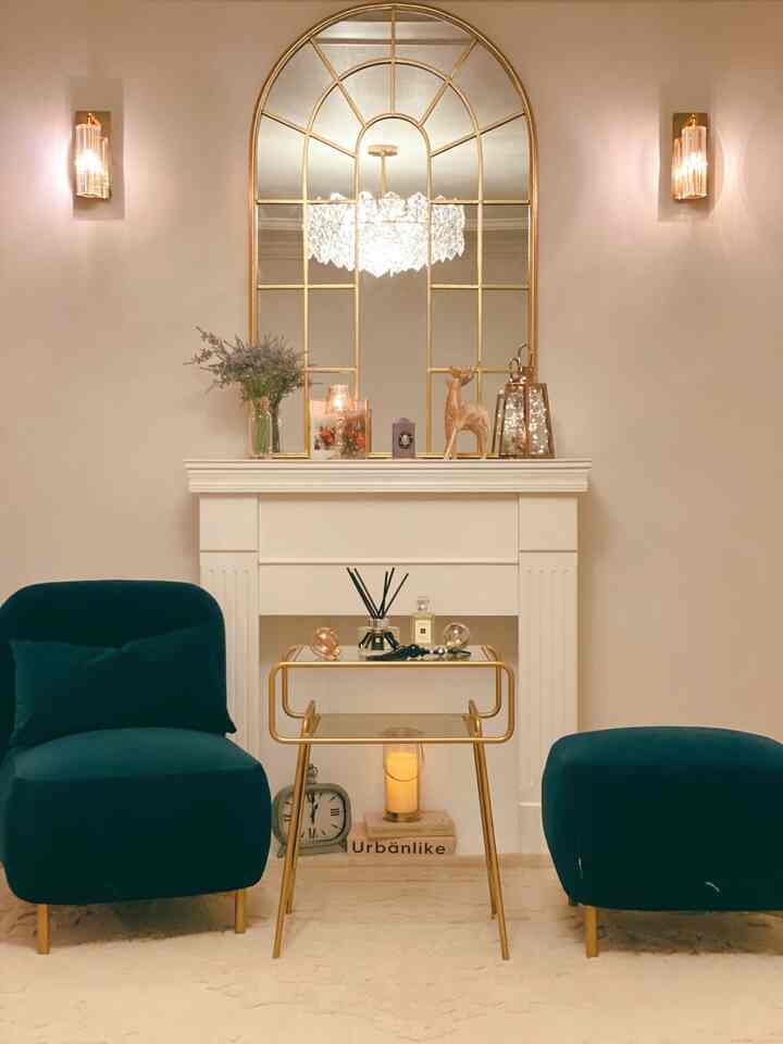 Modern cozy living room in gold and natural tones featuring a fireplace and two armchairs