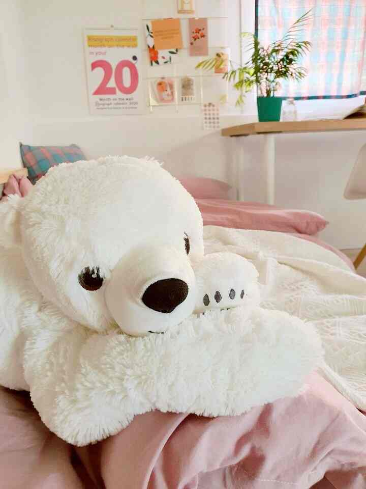 White and pink toned bedroom featuring a large polar bear plush and patterned curtains creating a cozy atmosphere