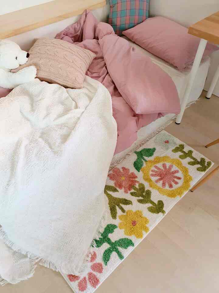 Pink and white toned studio bedroom featuring bed with floral rug, creating a cozy atmosphere
