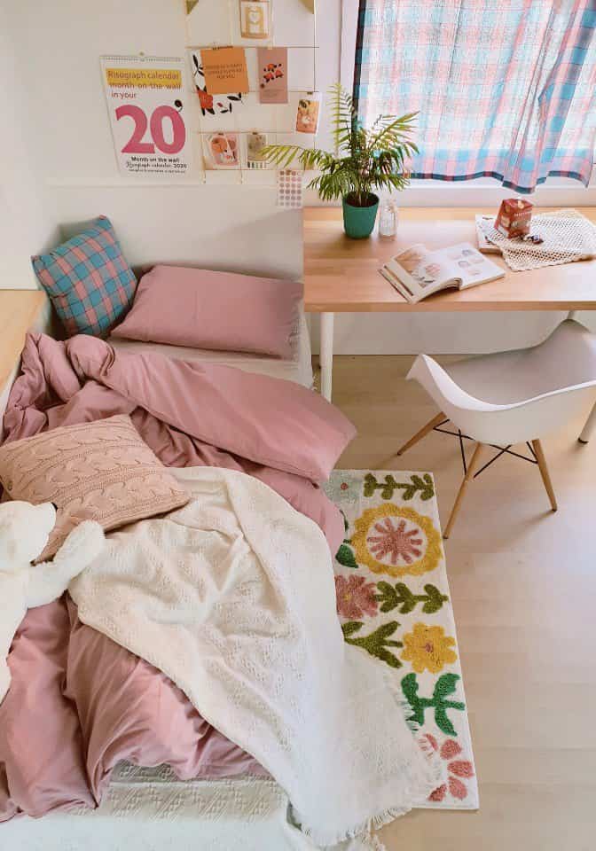Cozy studio bedroom featuring pink bedding and natural wood desk with warm harmonious tones