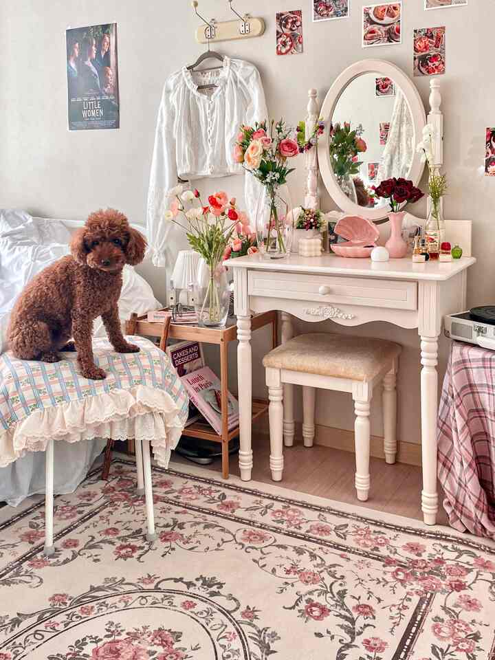 Natural color vintage French country bedroom featuring flowers, a vanity, and a dog creating a cozy atmosphere